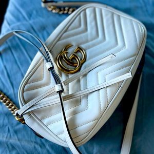 Light cream color Gucci bag with long strap.